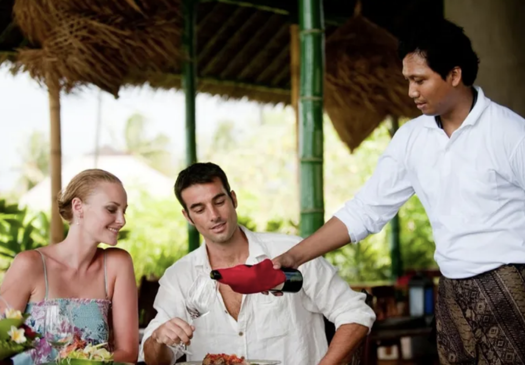 Person serving drinks to couple at bar